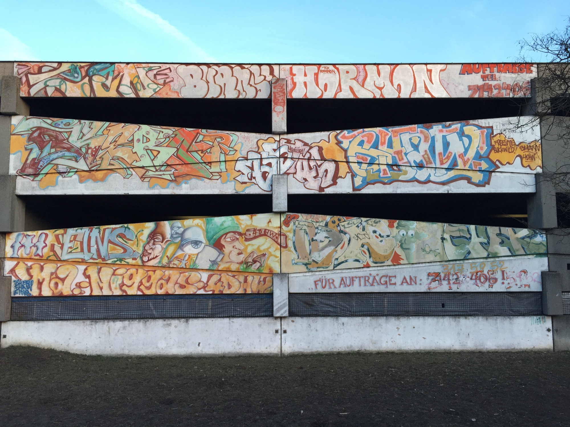 Graffiti an der Außenwand eines Parkhauses mit Telefonnummer des Künstlers/der Künstlerin für Auftragsannahme