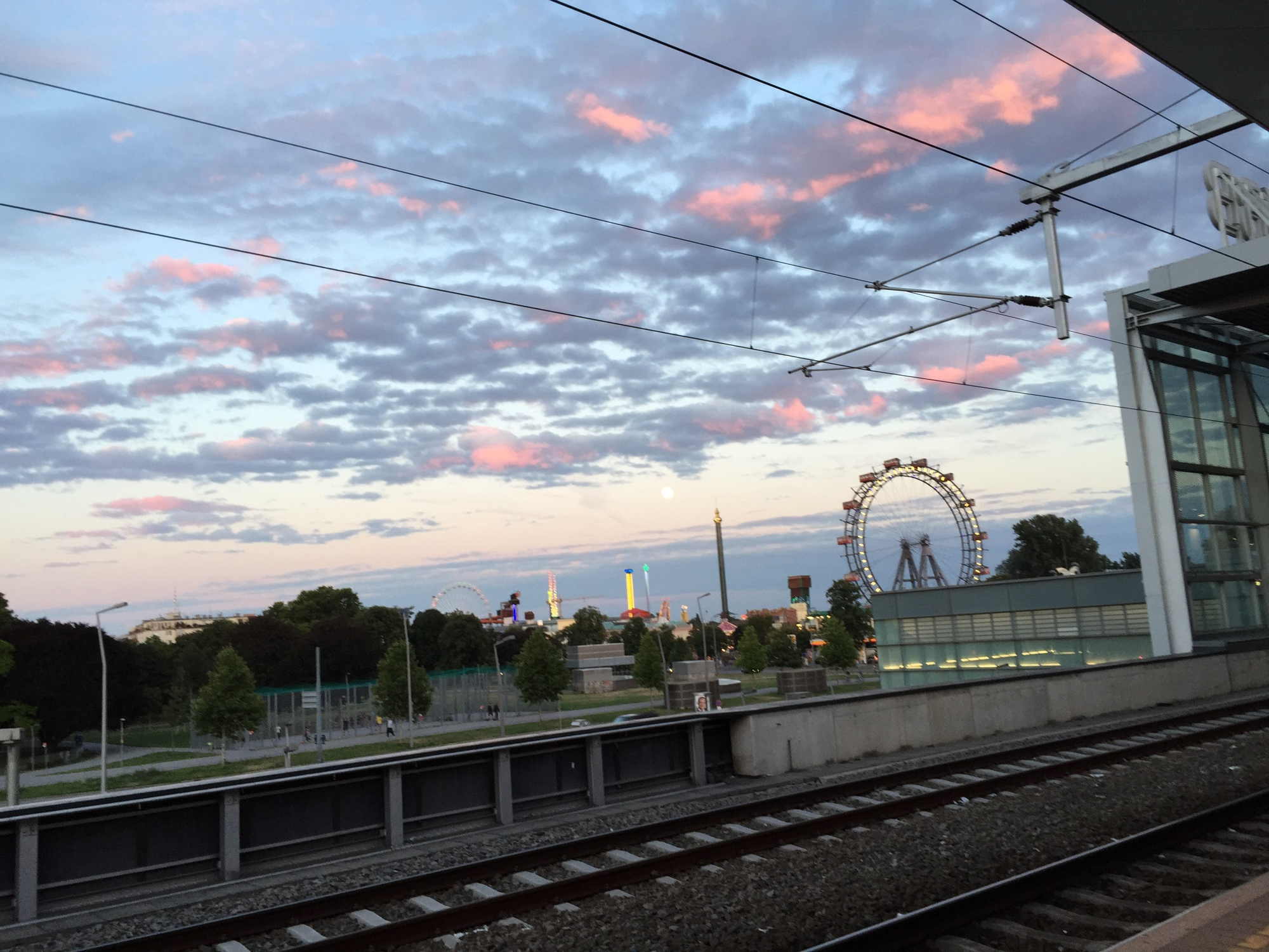 Bahnhof Wien Praterstern, abendlicher Blick vom Bahnsteig 4 auf den Prater, Mond schwer zu erkennen links neben der Spitze des hohen Kettenkarussels