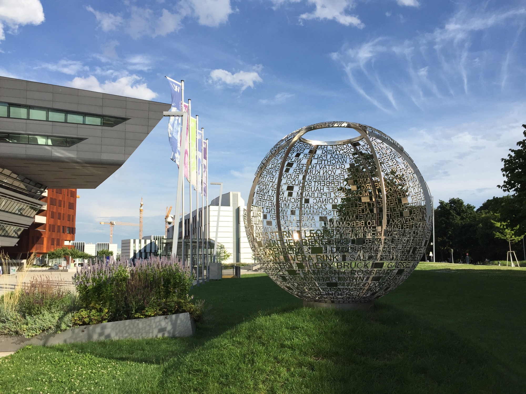 Gedenkprojekt der WU, Metallkugel mit Namen mit Blick auf WU-Gebäude dahinter