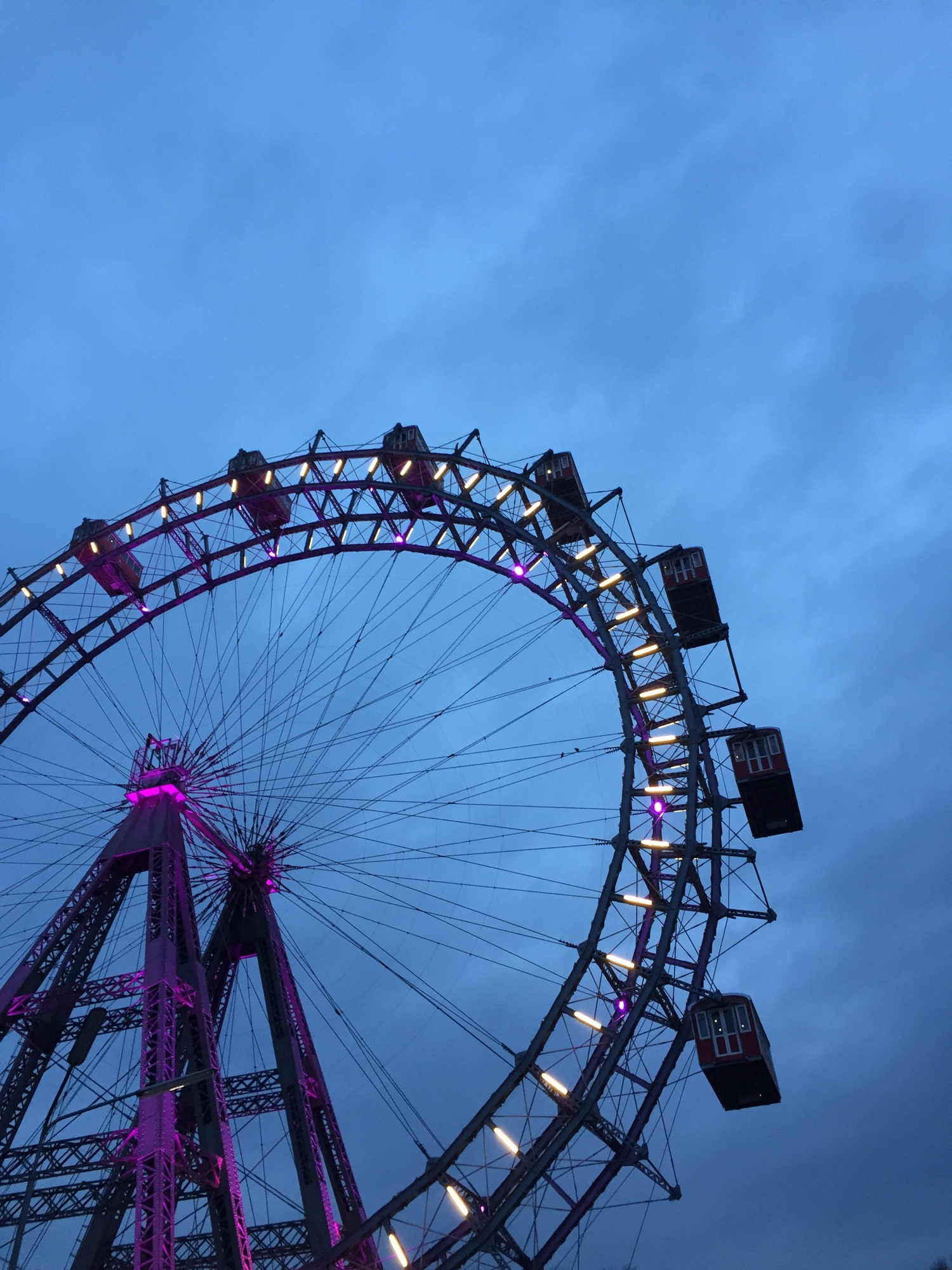 Riesenrad im Wiener Prater, violett beleuchtet mit bläulich dämmerndem Wolkenhimmel im Hintergrund