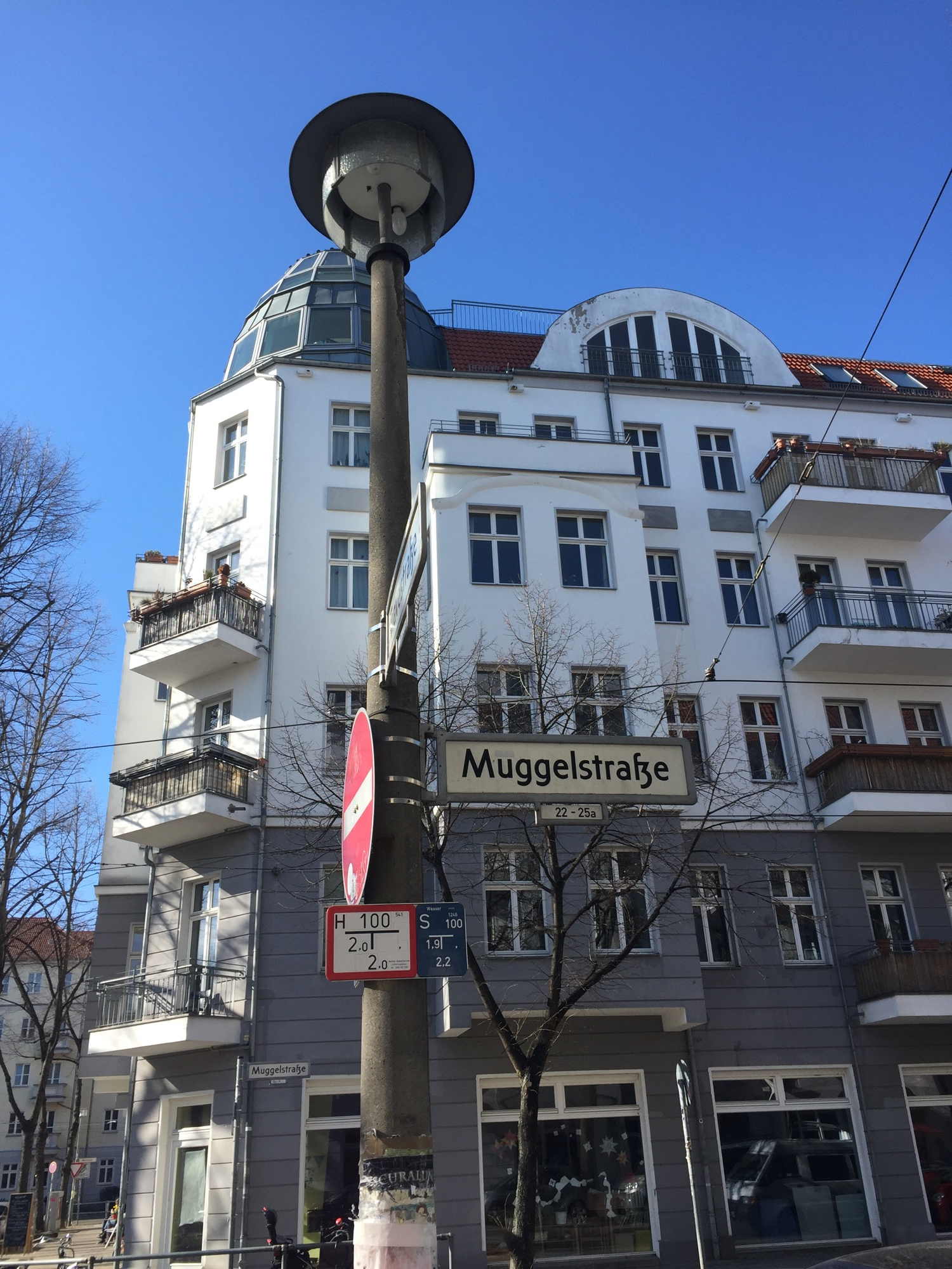 Muggelstraße in Berlin Friedrichshain, Straßenlaterne, Straßenschild, imposantes Eckhaus im Hintergrund