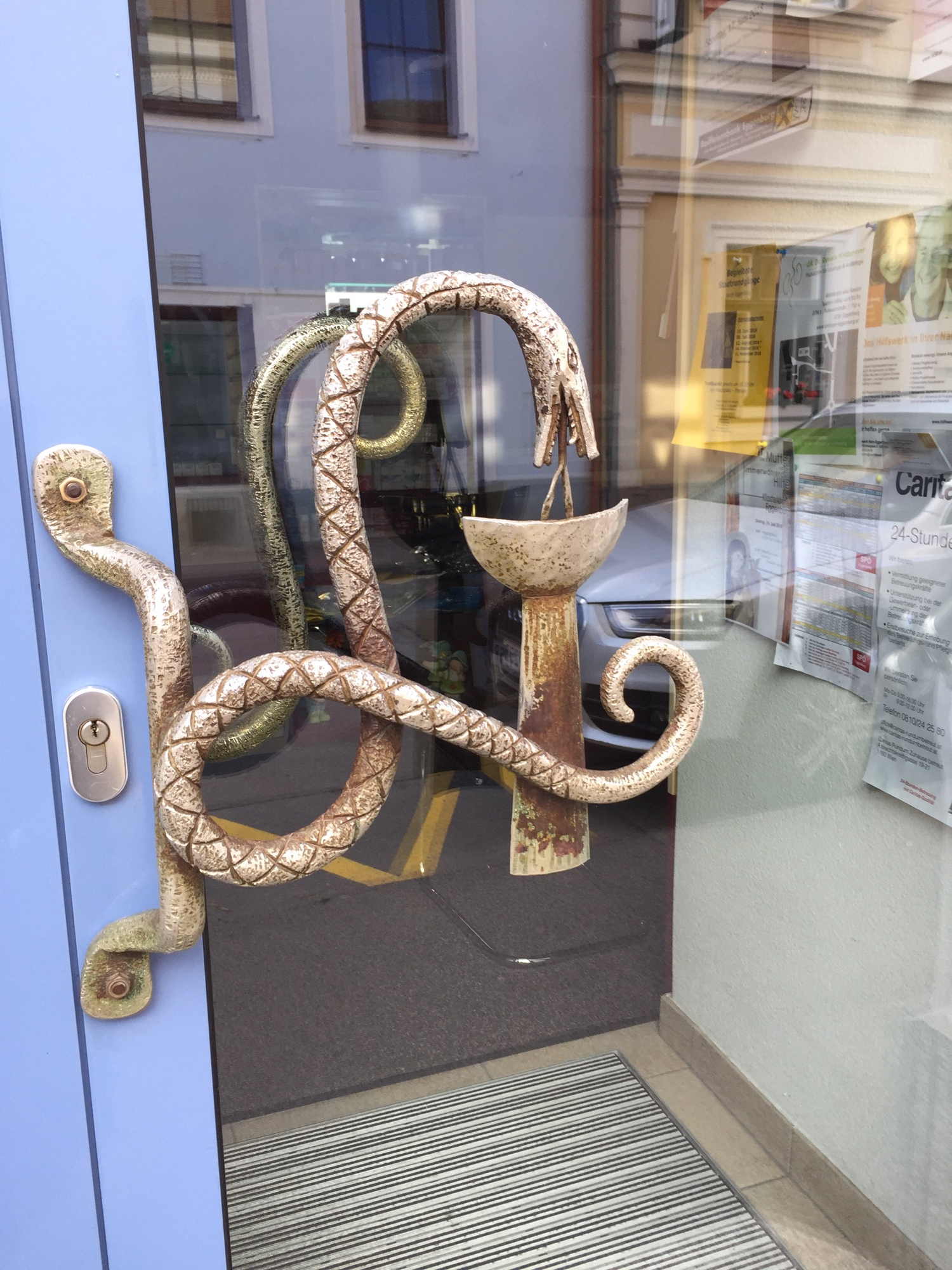 Türgriff in Form einer Aesulap-Natter an der Tür einer Apotheke in Eggenburg