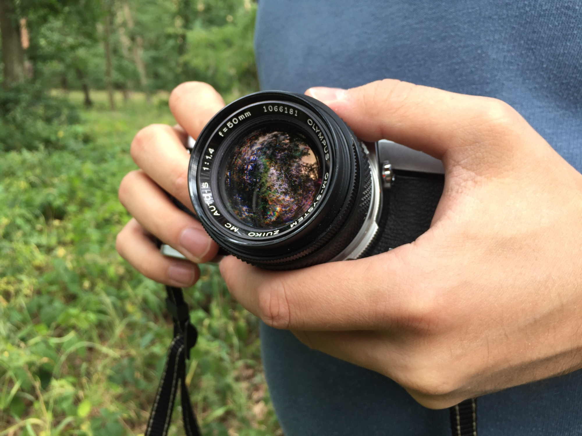 im Objektiv des Fotografen spiegeln sich Wald und Himmel