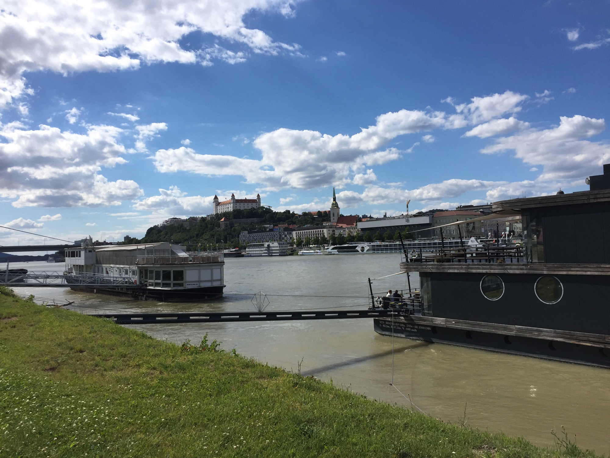 Blick auf die Burg von Bratislava vom südlichen Donauufer aus, Discoschiffe im Vordergrund