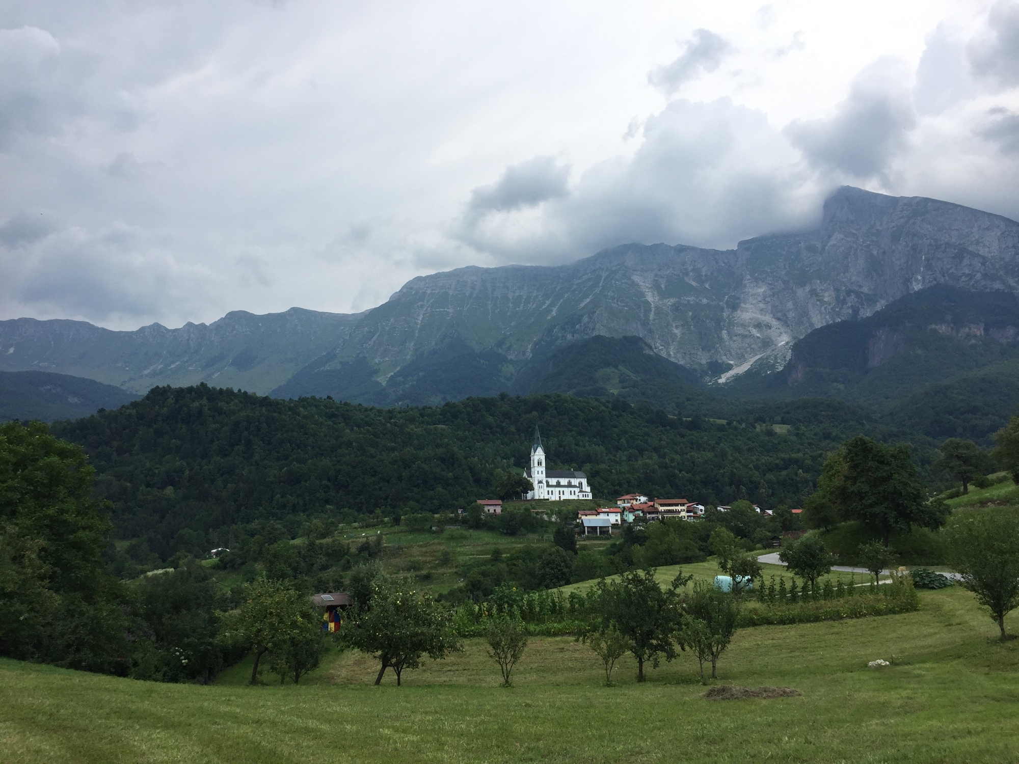 Blick auf die Kirche von Drežnica mit Berg- und Wolkenpanorama im Hintergrund