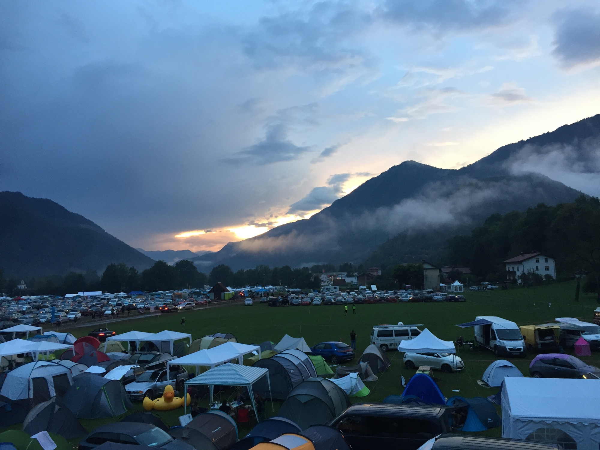 Sonnenuntergang zwischen den Bergen mit Blick über Zelte auf dem Campingplatz