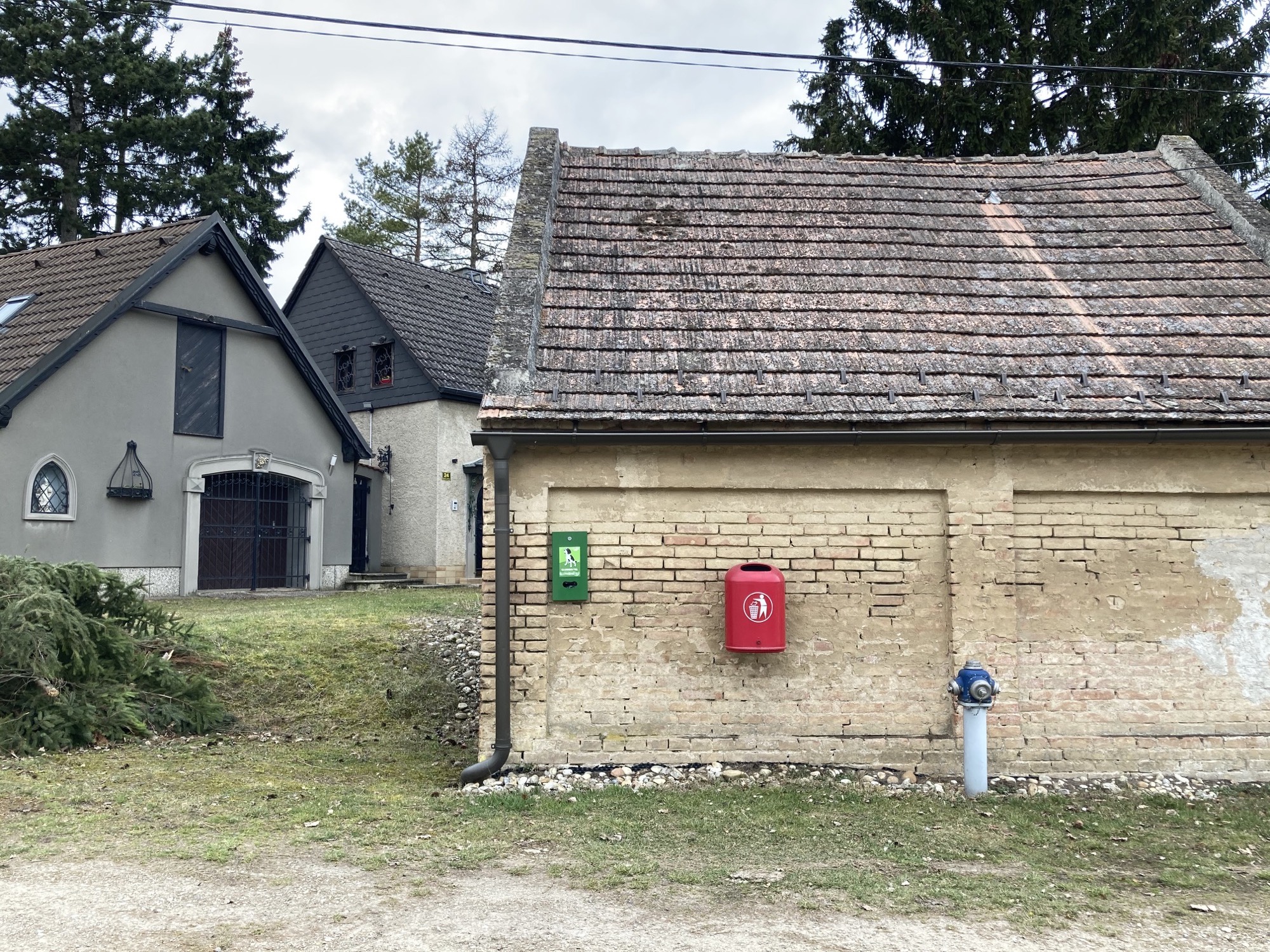 Keller mit Ziegelwand, rotem Mistkübel und Hydrant