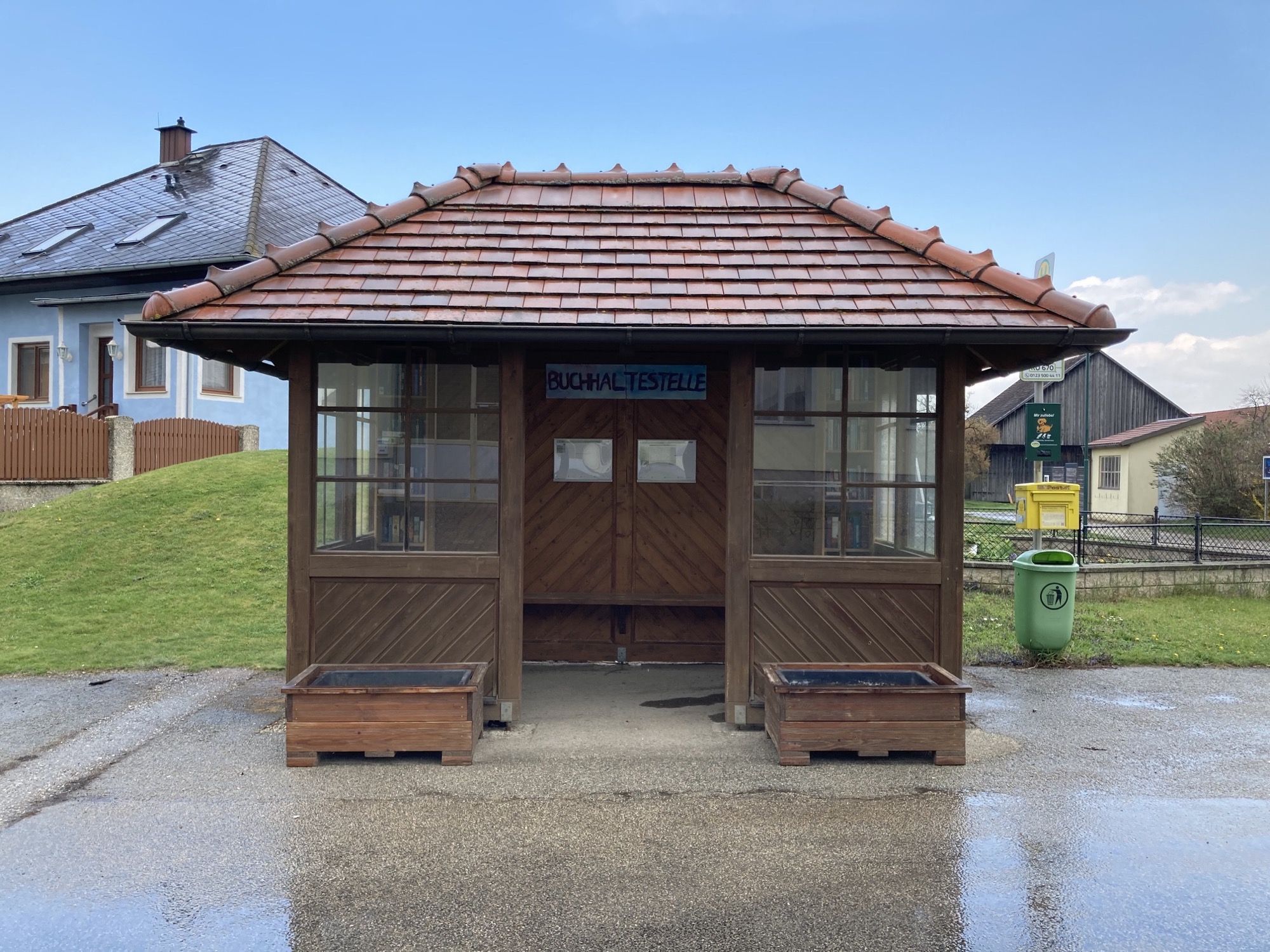Bushaltestelle mit dem Schild „Buchhaltestelle“, links und rechts im Häuschen sind Bücherregale zu erkennen