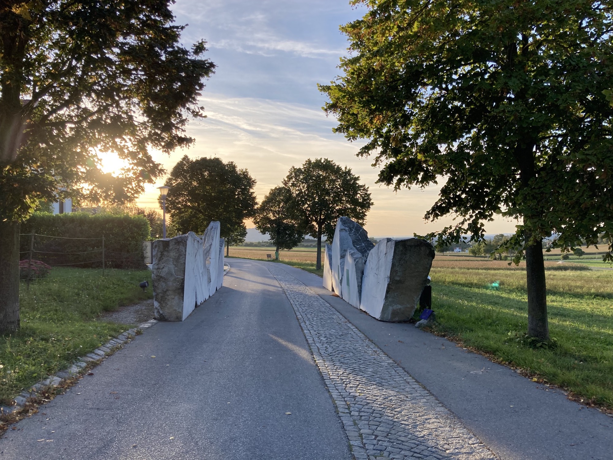 Station 1, 8 Steinblöcke, links und rechts des Weges, der Weg macht nach den Steinblöcken eine Linkskurve, von dort leuchtet das Herbstlicht