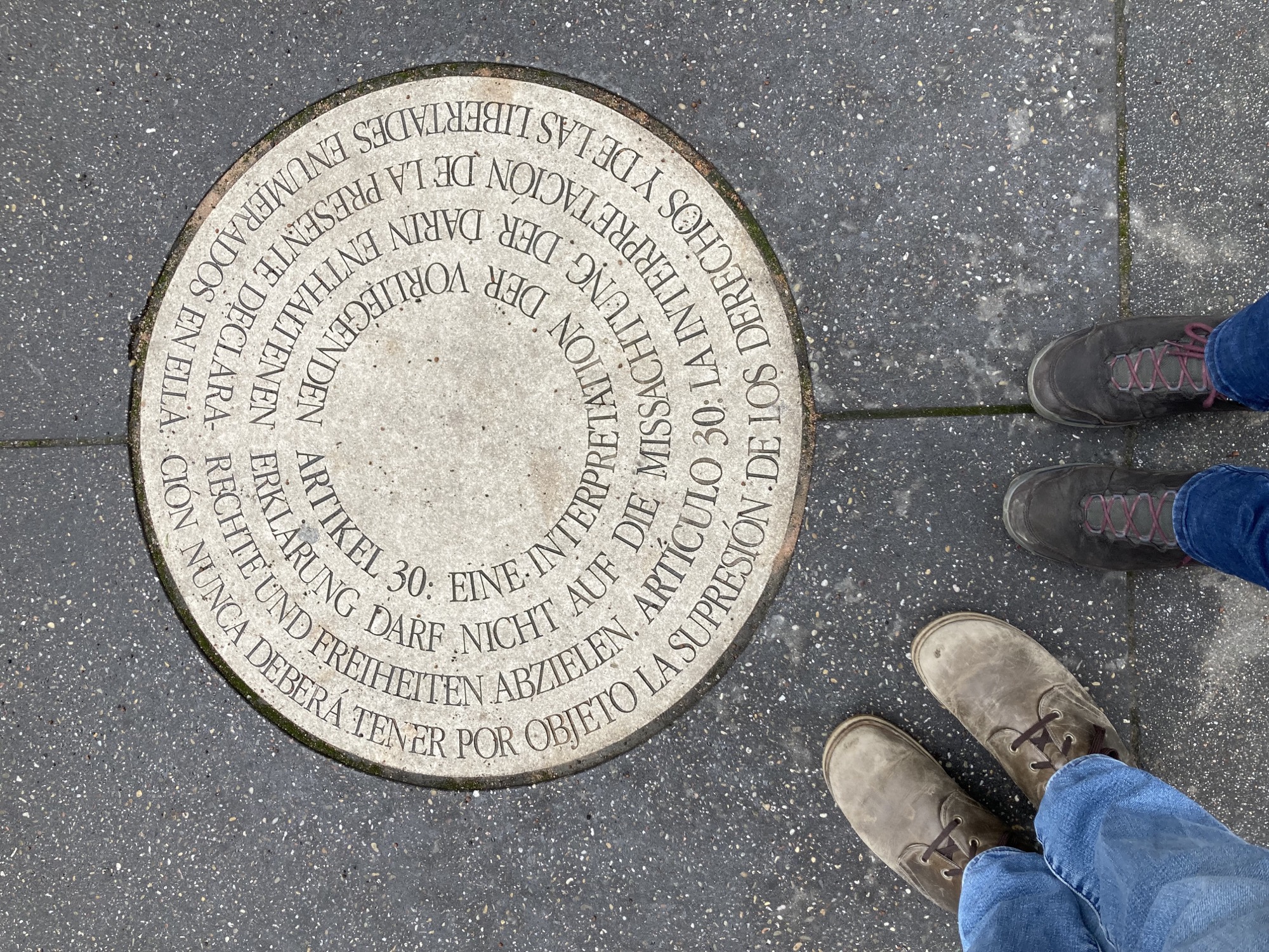 Artikel 30 der Deklaration der Menschenrechte, eingelassen in einer runden Bodenplatte, daneben die Füße mit Schuhen von zwei Menschen