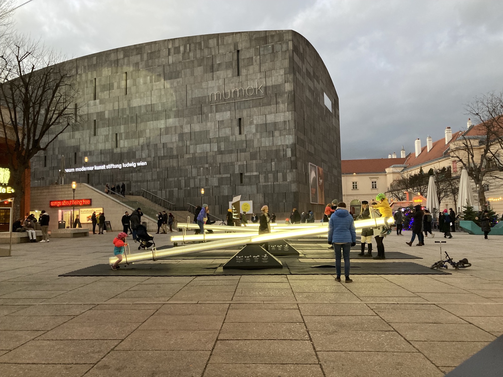 Kunstinstallation in Form von Wippen, die durch Bewegung Licht- und Soundeffekte auslösen, im Hintergrund das Museum mumok