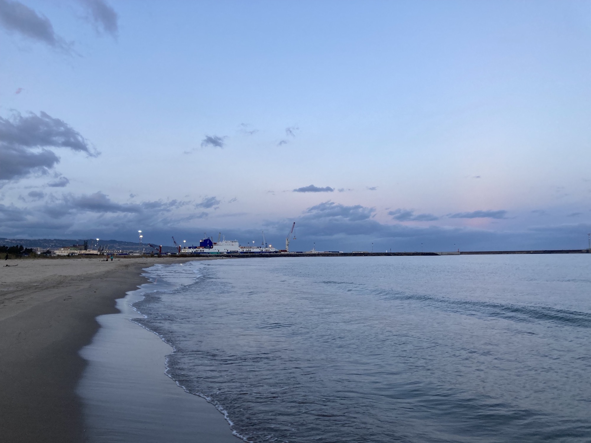 Strand von Catania im Abendlicht, Blick Richtung Hafen, wo gerade ein Containerschiff beladen wird