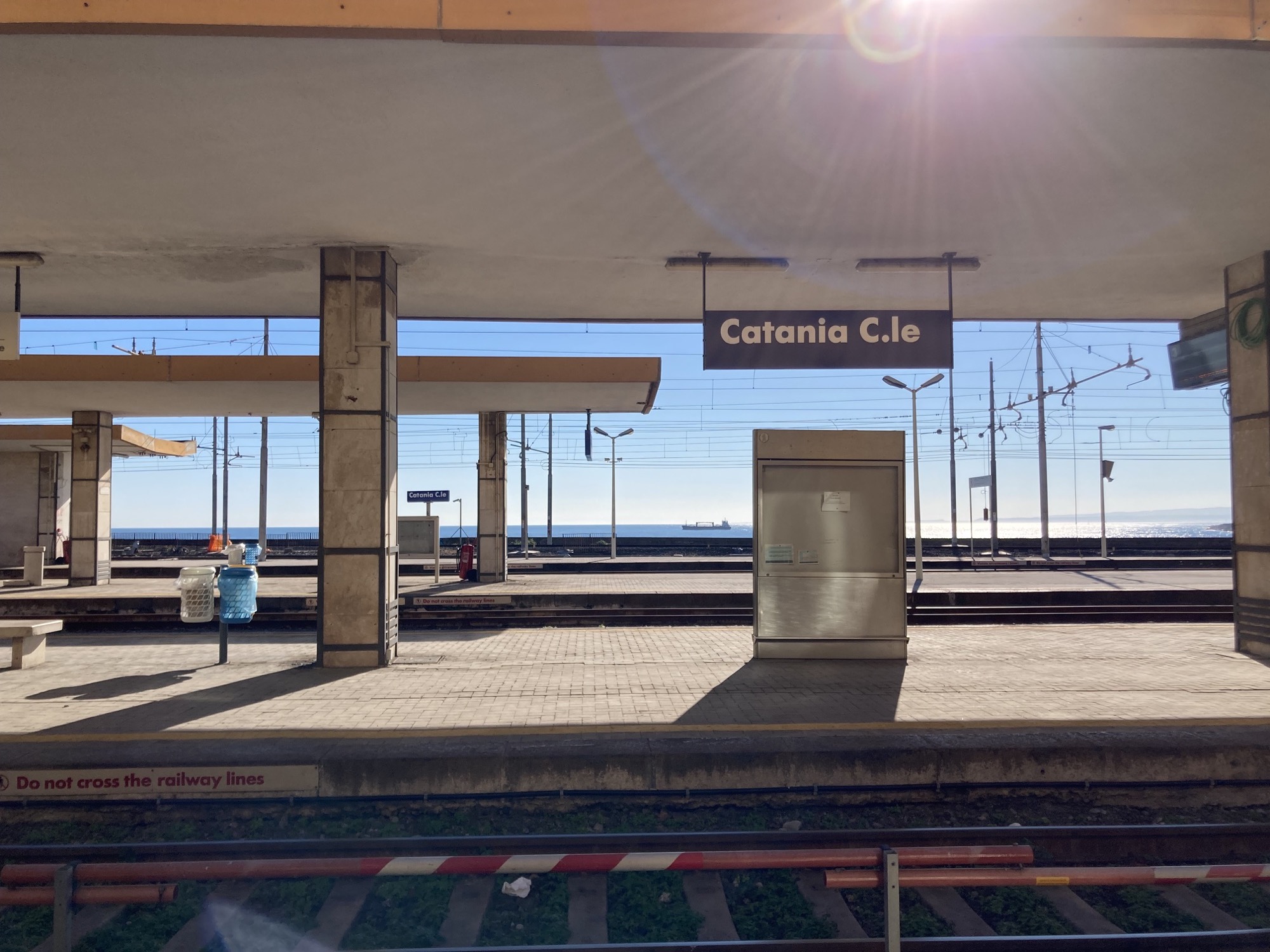 Bahnhof Catania Centrale, im Vordergrund die Bahnsteige, im Hintergrund das Meer mit einem Frachtschiff