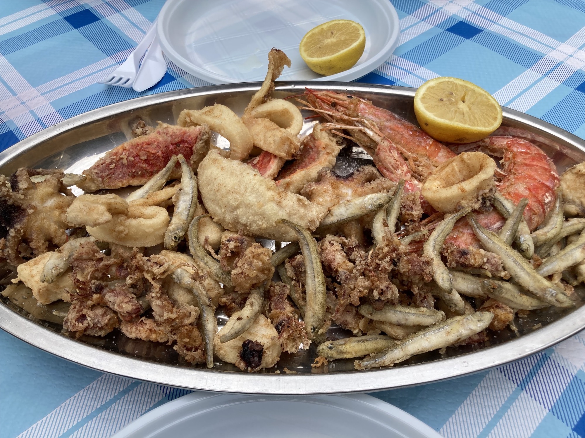 Frittura Mista, gemischte frittierte Meeresfrüchte auf einem Metalltablett, mit Zitrone als Deko