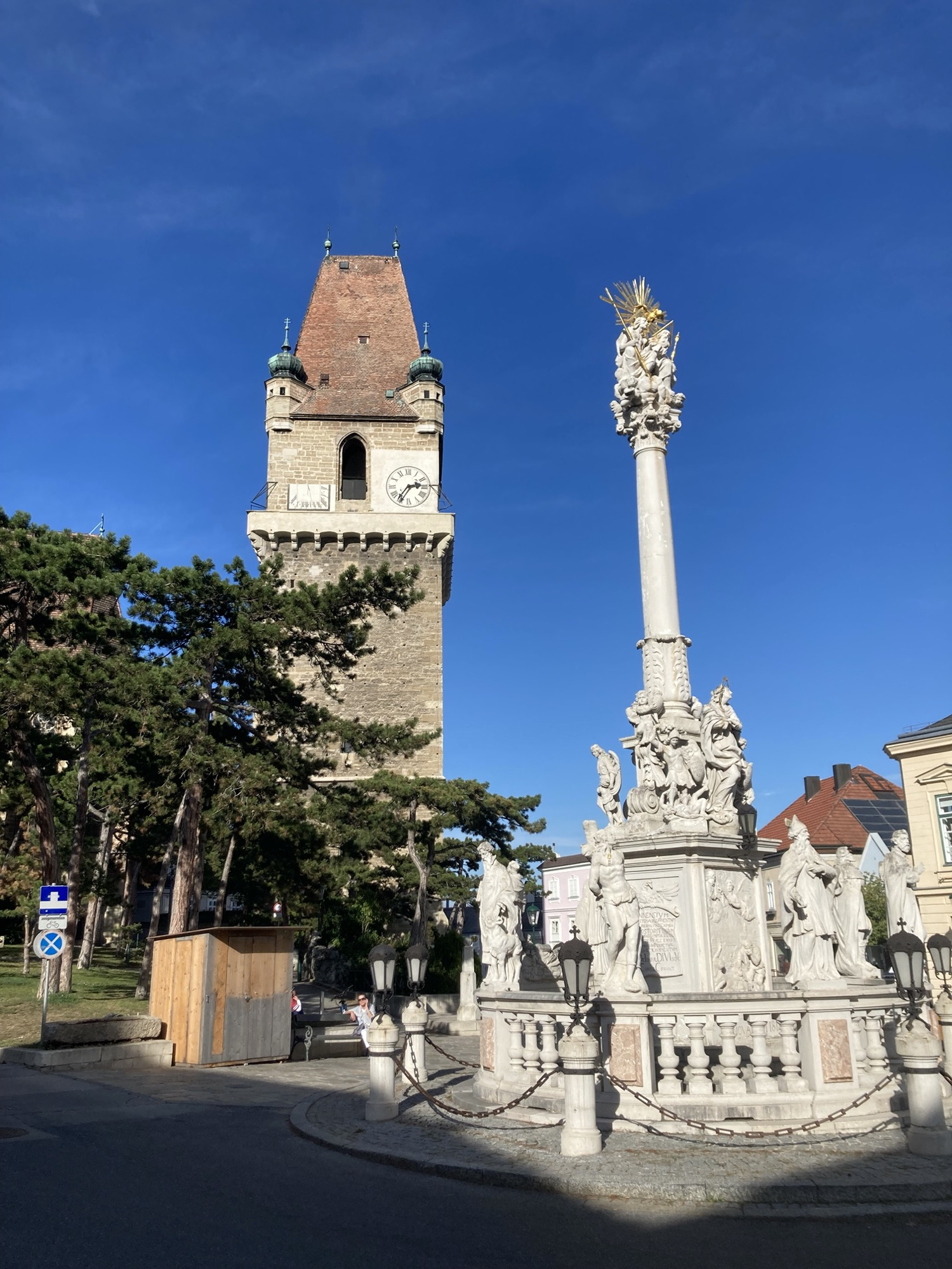 Wehrturm und Pestsäule auf dem historischen Marktplatz in Perchtoldsdorf vor blauem Himmel