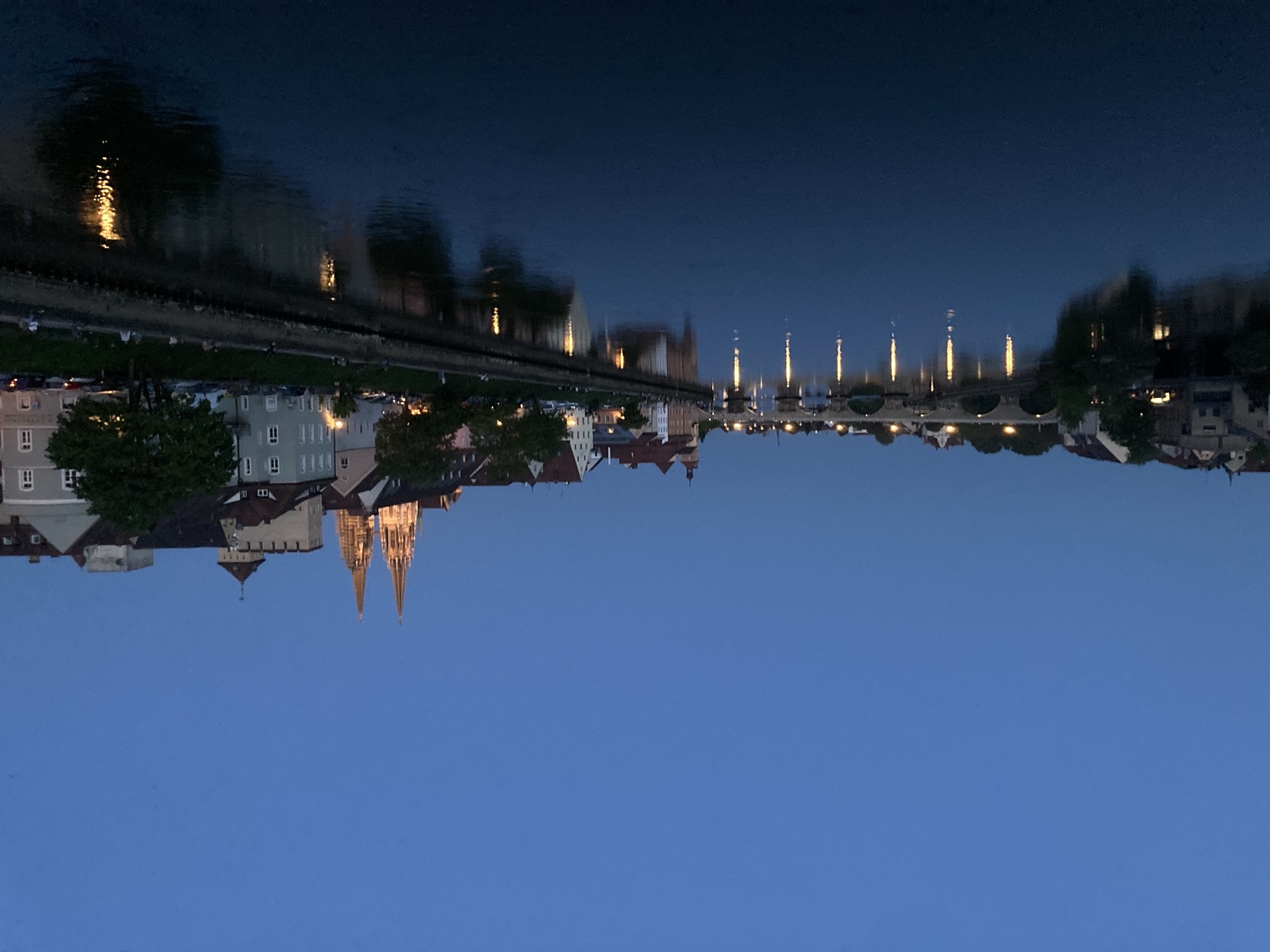 Abendansicht der Donau über Regensburg, Uferpromenade, steinerne Brücke, rechts ragen die zwei Türme des Doms über die Dächer der Altstadt