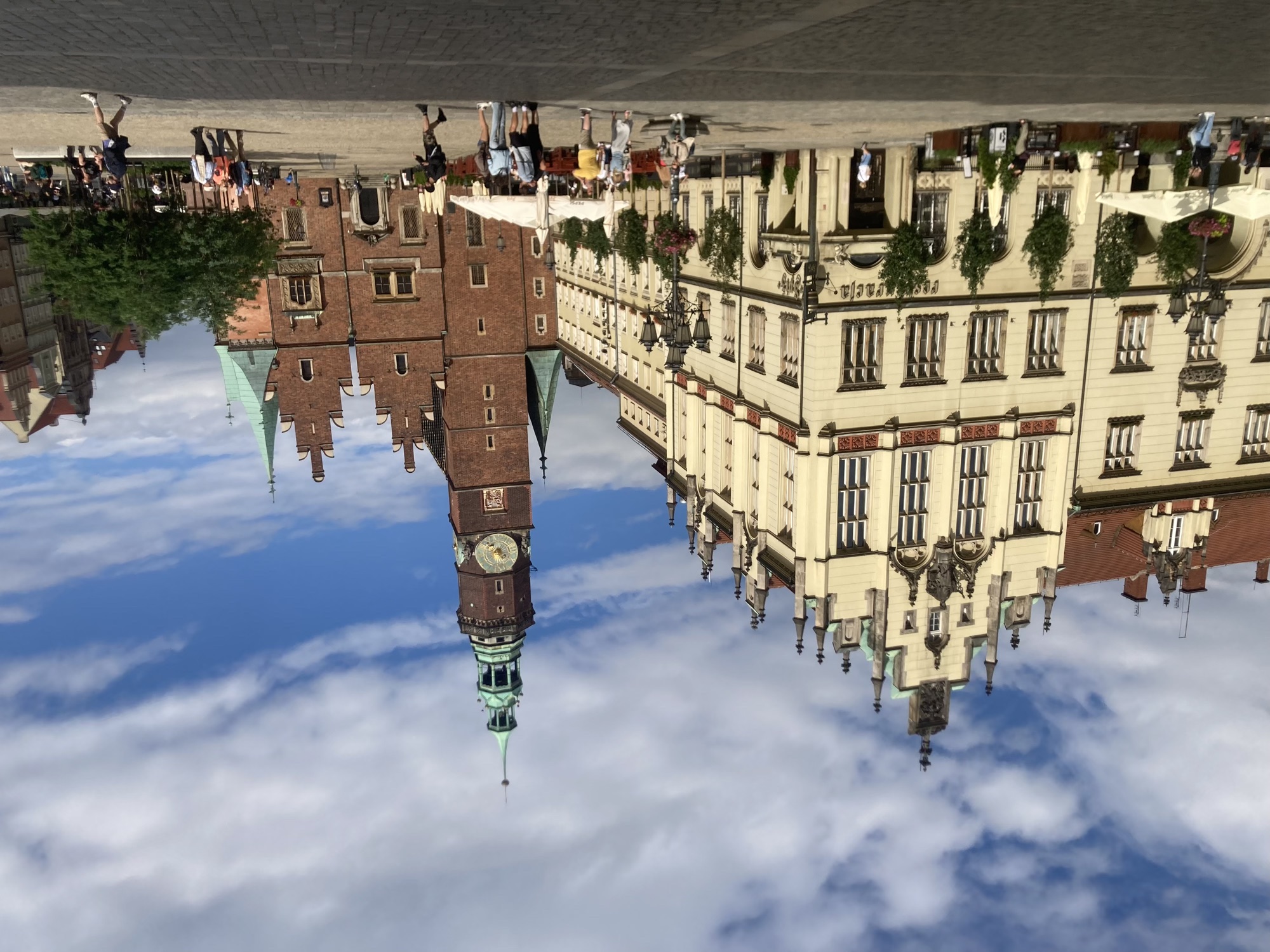 andere Seite des Rathausplatzes, links ein helles Gebäude mit hohen Fenstern und Türmchen, rechts eine Backsteinkirche mit einem hohen Turm, der von einer grünen Kuppel gekrönt ist