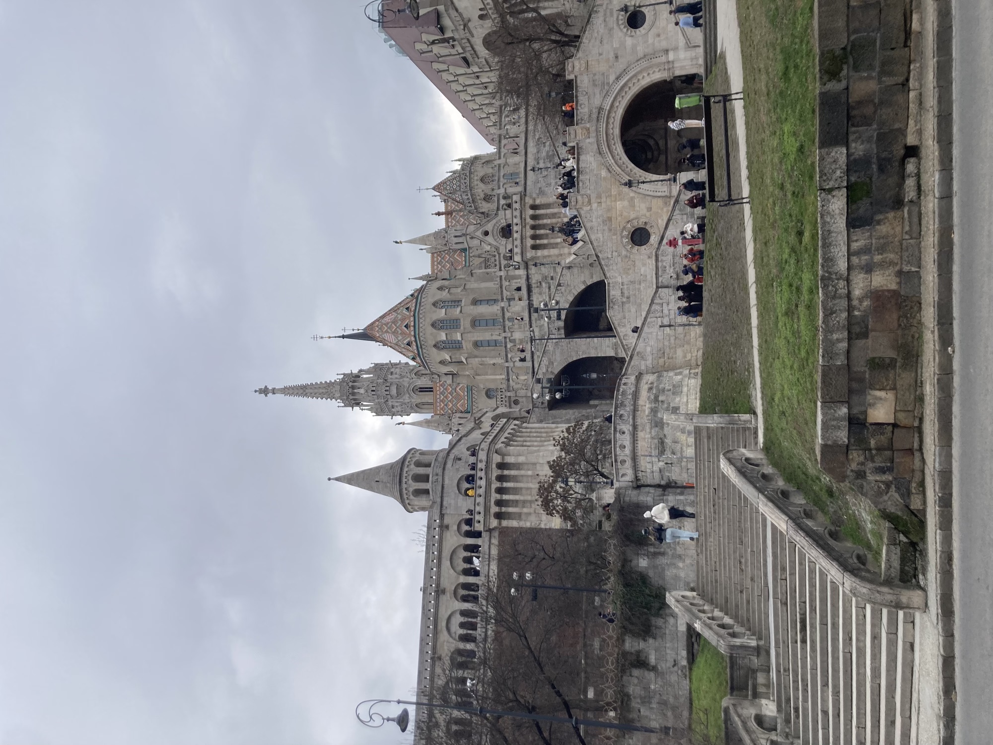 Fischerbastei, unten breite Treppen, dahinter dekorative Mauern mit Rundbögen und einer Turmspitze, dahinter die gotischen Türme der Matthias-Kirche